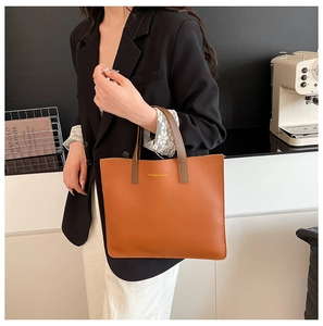 Bolso tote de cuero color caramelo con logotipo dorado y asas marrón oscuro