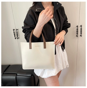 Primer plano del bolso tote crema con asas marrones y texto Fashion & Bags en modelo