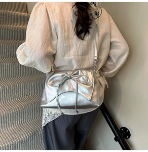 Sac bandoulière argenté métallisé avec nœud porté par un mannequin en escalier