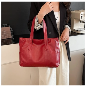 Detail of red large capacity tote bag with leather bark texture held by a model