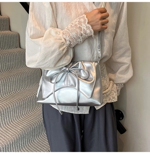 Détail du sac à bandoulière argenté métallisé avec nœud et fine bandoulière chaîne