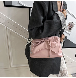 Détail du sac à bandoulière rose avec nœud décoratif et breloque en perles