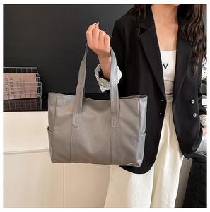 Dettaglio della texture di una borsa tote grigia in pelle e tasca laterale su modella