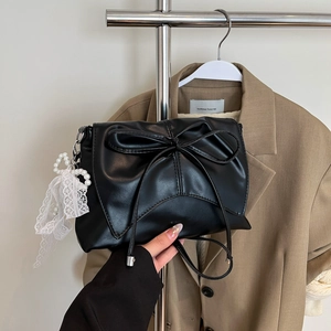 Détail du sac à bandoulière noir avec grand nœud et pendentif en perles et dentelle