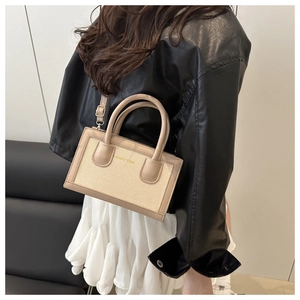 Side view of beige woven crossbody bag with leather trim and AMILY 1986 logo on model