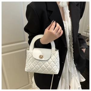 Detail of white quilted handbag with gold metal lock and chain strap on a model