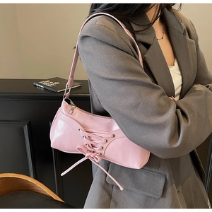 Detail of pink shoulder bag featuring decorative cross lacing and chic bow design