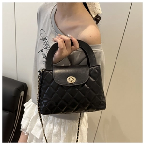Detail of black quilted leather handbag featuring a golden metal twist lock and chain strap