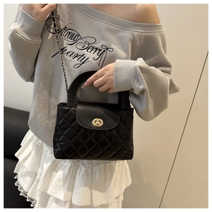 Detail of black quilted leather handbag with gold twist-lock and chain strap