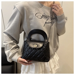 Detailed view of black quilted chain bag featuring golden twist lock and leather handle