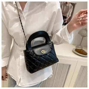 Detail of black quilted leather handbag featuring a gold turn-lock and chain strap