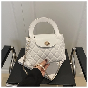 Detail of white quilted texture and golden twist lock on stylish chain handbag