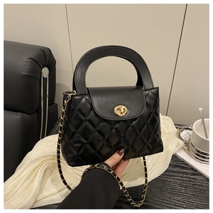 Detail of black quilted leather handbag with gold twist lock and chain strap