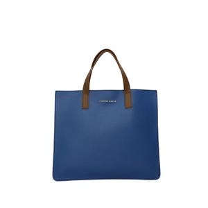 Bolso tote minimalista de cuero azul marino con asas marrones y logo dorado en fondo blanco