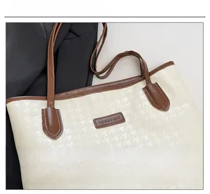 Detail of houndstooth textured tote bag with brown leather trim and fashion logo label
