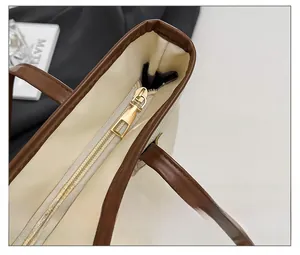 Detailed macro shot of the smooth gold metal zipper and leather trim on this tote bag