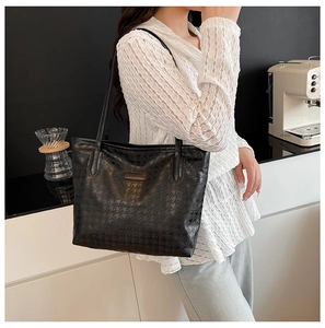 Close-up of black houndstooth patterned tote bag showing shoulder strap and side view