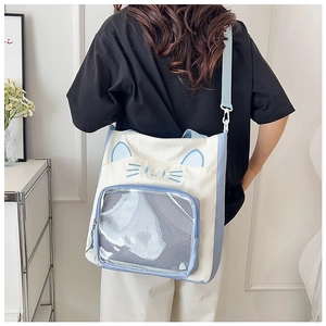 Detail einer niedlichen Canvas-Ita-Bag mit Katzenmotiv, PVC-Fenster und blauem Gurt