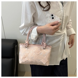 Detailed close-up of pink lace handbag featuring floral textures and 3D butterfly appliqués