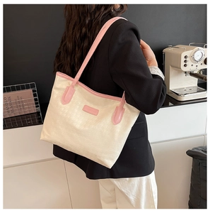 Side view of large houndstooth tote bag with pink leather straps worn by a model
