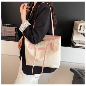 Detail of houndstooth tote bag featuring pink leather handles and fashion nameplate