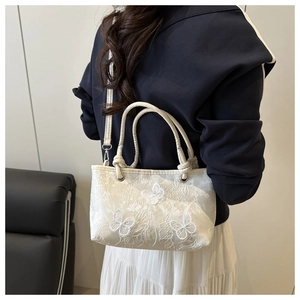 Close-up of white lace handbag featuring 3D butterfly embroidery and mesh texture