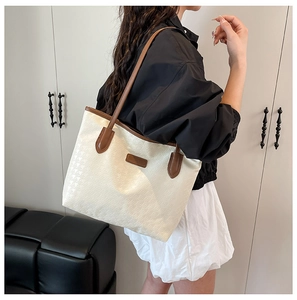 Detailed view of women's houndstooth tote bag with brown leather trim and shoulder straps