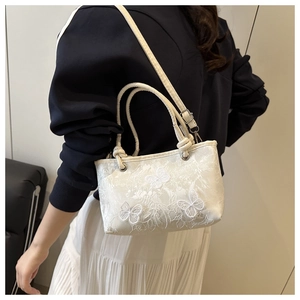 Detail of sweet lace butterfly embroidery on a white satin shoulder bag with silver hardware