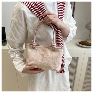 Detail of light pink lace handbag featuring 3D butterfly appliques and twisted handle