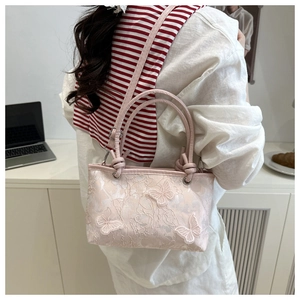Detail of pink lace shoulder bag featuring 3D butterfly embroidery in a lifestyle setting