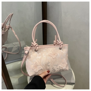 Detail of pink floral butterfly embroidery and knotted handle on the fashion handbag