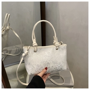 Dettaglio ravvicinato della borsa in pizzo bianco con delicati ricami di farfalle 3D