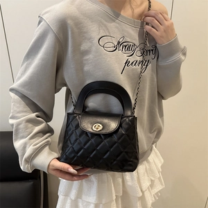 Black quilted crossbody bag with gold turn-lock and chain strap shown on model
