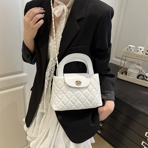 White quilted flap bag with gold twist lock and chain strap shown on a model