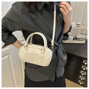 Détail d'un sac Boston blanc crème avec ferrures dorées et longue bandoulière réglable