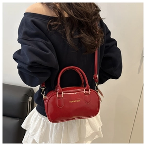 Red patent leather Boston bag with gold hardware and chain strap shown on a model