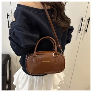 Sac bowling en cuir marron avec lettrage doré porté à l'épaule pour un style quotidien