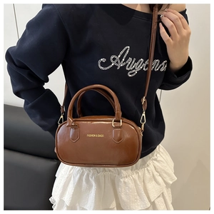 Detail of dark brown leather Boston bag with gold FASHION & BAGS lettering and hardware