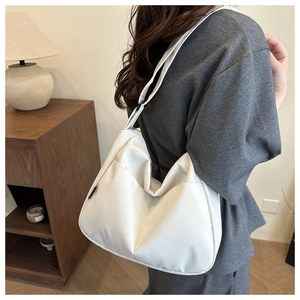 Minimalist white nylon crescent tote bag shown with adjustable strap on a female model