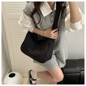 Detail of a large black nylon crossbody bag with wide shoulder strap and spacious side zip