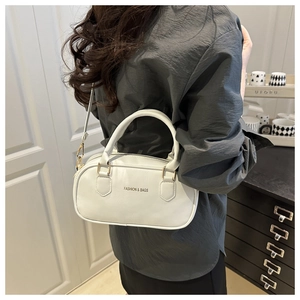 Détail d'un sac cylindrique blanc avec texte Fashion & Bags et finitions dorées