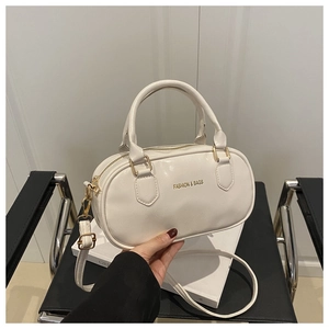 Détail d'un sac bowling blanc en cuir avec des accessoires métalliques dorés