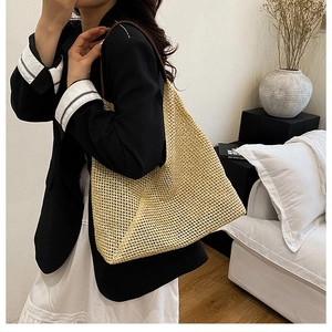 Detail view of woven straw tote bag with brown leather straps on an elegant model