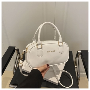 Détail du sac bowling blanc montrant les fermetures dorées, anses et bandoulière amovible