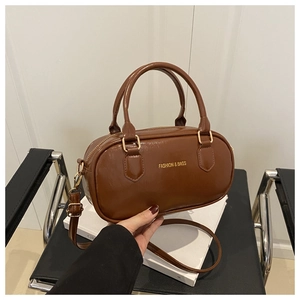 Détail d'un sac Boston en cuir verni marron avec garnitures dorées et bandoulière