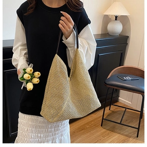 Detail of hand-woven straw tote bag with brown leather handles in a home setting