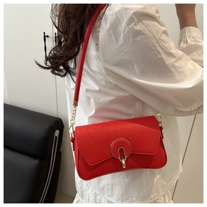 Detail of red leather shoulder bag featuring a gold round lock and chain strap