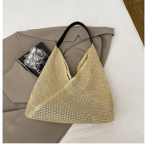 Detail of woven straw shoulder bag with brown leather straps on a beige blazer