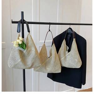 Detail of hand-woven straw tote bags with faux leather handles on a display rack