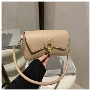 Detail of minimalist beige handbag with round gold metal lock and thick cylindrical strap